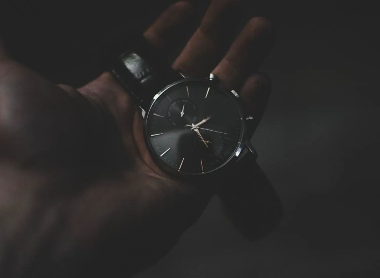 An AXIONX timepiece held in the hand